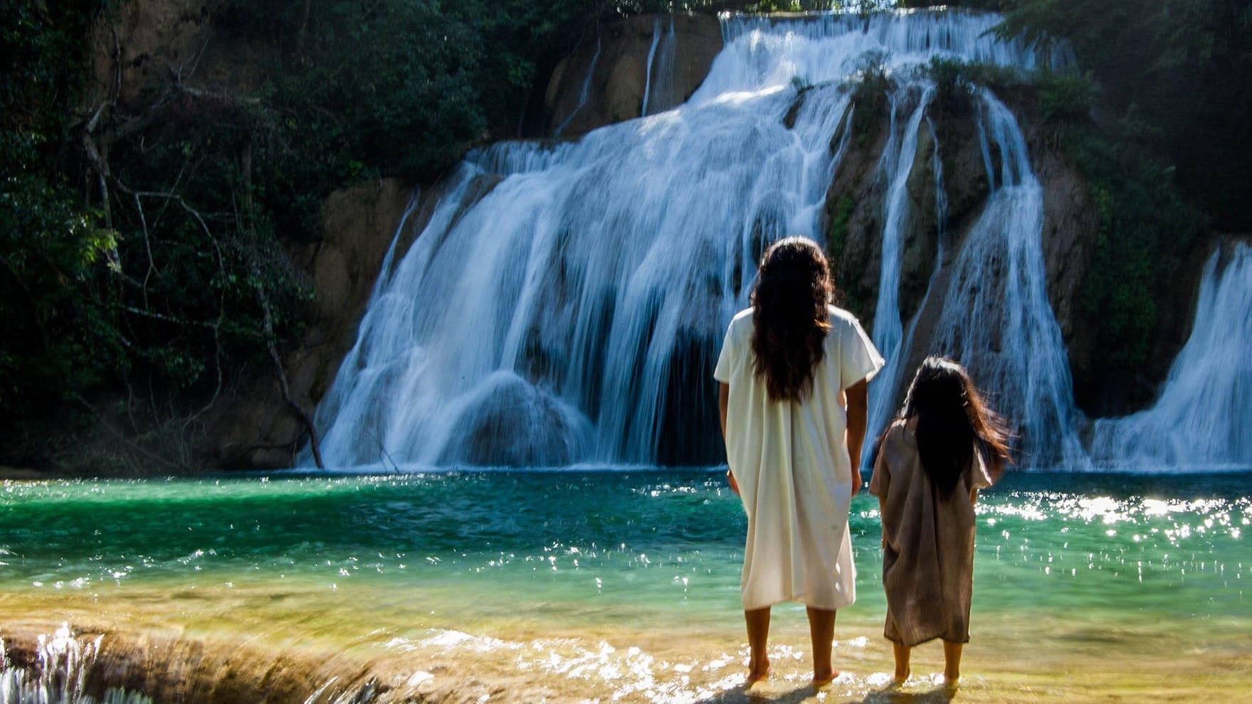 Deux personnes indigènes devant une cascade dans le Chiapas au Mexique.